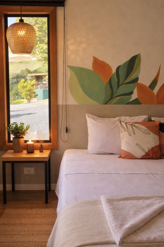 Suíte privativa com roupa de cama clara, janelas e madeira.